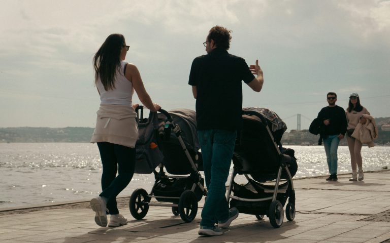 zdjęcie matki i ojca spacerujących z dziećmi w wózkach