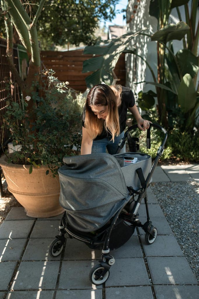 matka pochylająca się nad wózkiem dla dziecka