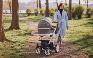 Młoda mama spaceruje po parku, prowadząc elegancki wózek z gondolą – polskie wózki dziecięce na codzienne spacery
