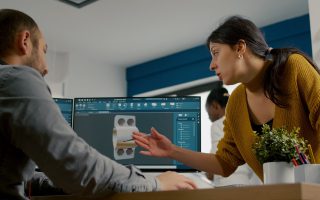 Inżynierowie omawiają projekt elementu konstrukcyjnego na ekranie komputera, modelowanie 3d w budownictwie w programie CAD