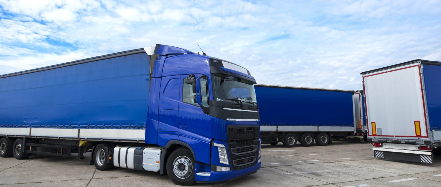 Niebieski tir z naczepą typu plandeka zaparkowany na placu manewrowym, stanowiący część floty realizującej transport farmaceutyczny w Bydgoszczy.