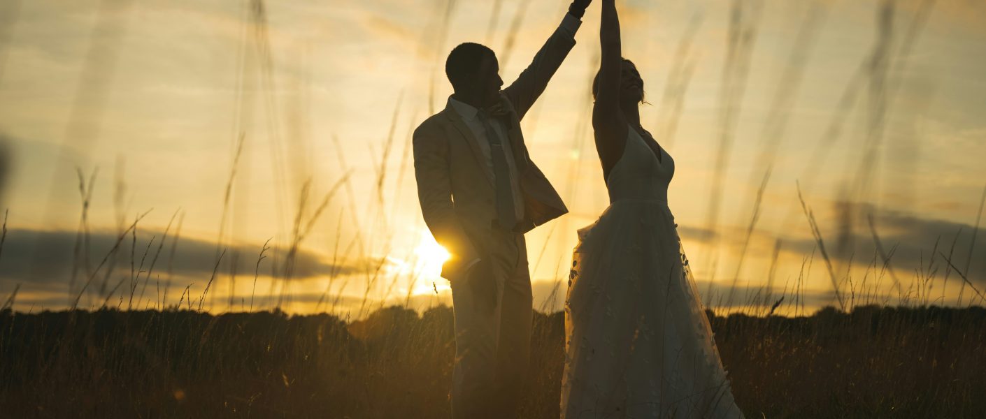 Na zdjęciu widać parę tańczącą na tle zachodzącego słońca