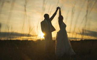 Na zdjęciu widać parę tańczącą na tle zachodzącego słońca