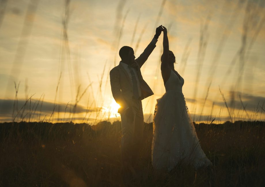 Na zdjęciu widać parę tańczącą na tle zachodzącego słońca