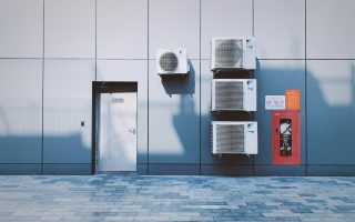 zdjęcie przedstawia fragment elewacji nowoczesnego budynku wykończonego dużymi, szarymi panelami.