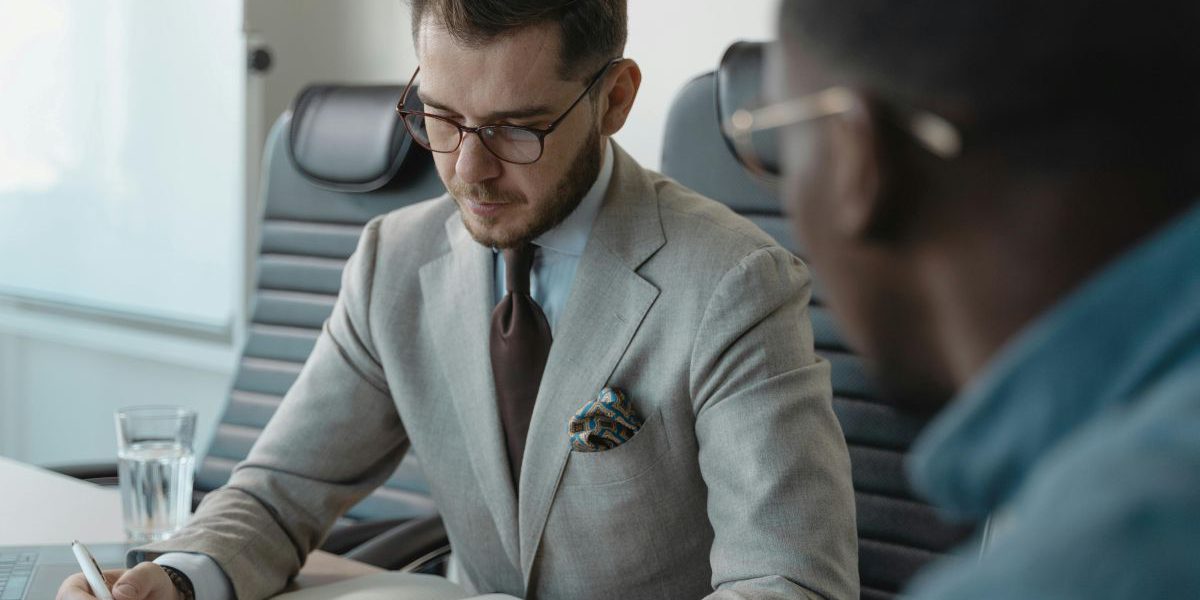 Profesjonalny doradca finansowy we Wrocławiu podczas konsultacji z klientem w nowoczesnym biurze, omawiający strategię inwestycyjną i dokumenty.