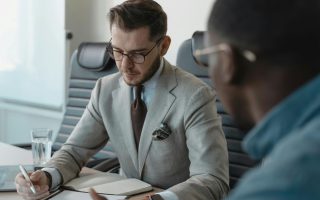 Profesjonalny doradca finansowy we Wrocławiu podczas konsultacji z klientem w nowoczesnym biurze, omawiający strategię inwestycyjną i dokumenty.