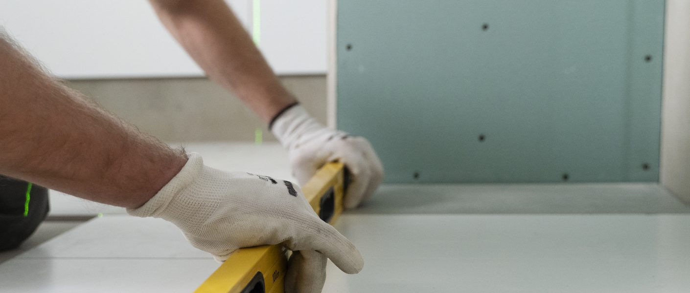 mężczyzna układa płytki przy pomocy poziomica - remont kuchni gdynia