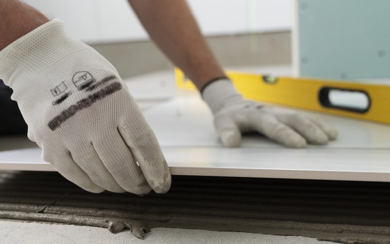 mężczyzna w ręakiwckach kładący płytki - remonty trójmiasto