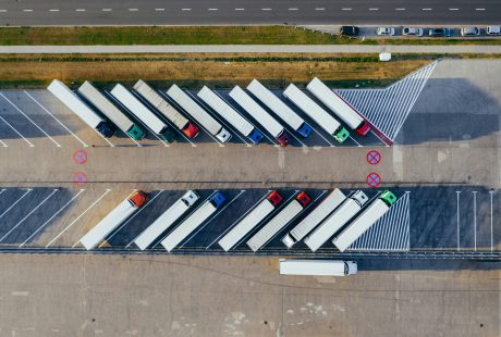 Na zdjęciu widok z lotu ptaka przedstawia parking dla samochodów ciężarowych z ustawionymi równolegle naczepami.